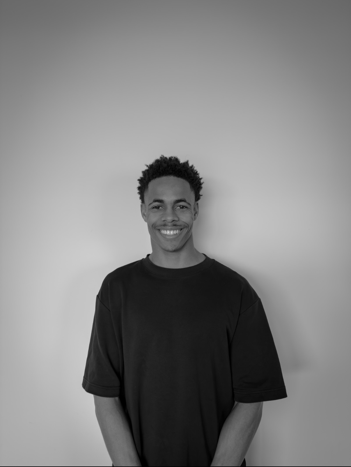 Portrait of a man with brown hair and glasses on a flat gray background.